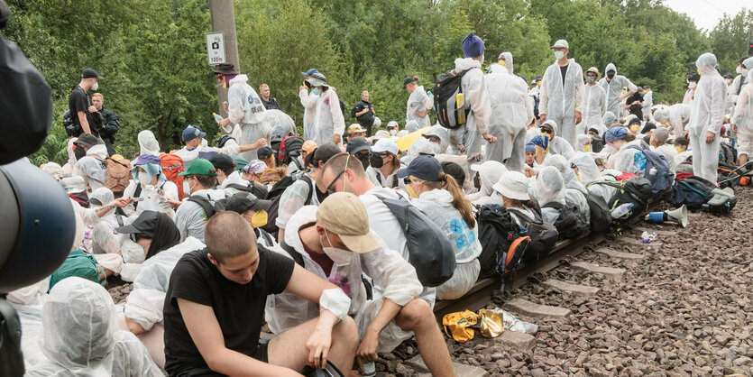 Aktivist:innen sitzen auf Bahngleisen