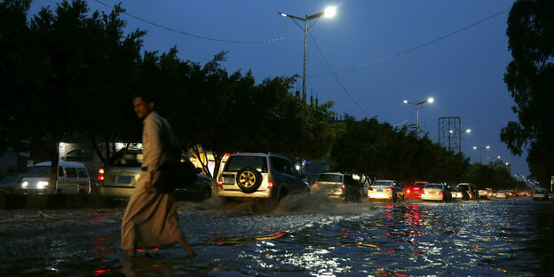 Jemen, Sanaa: Ein Mann überquert eine stark befahrene Straße, die nach heftigen Regenfällen überflutet ist