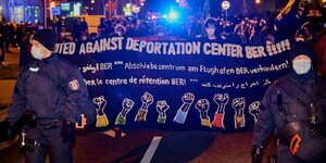 Demonstranten tragen Transparent mit der Aufschrift "United against Deportation Center BER!!!"