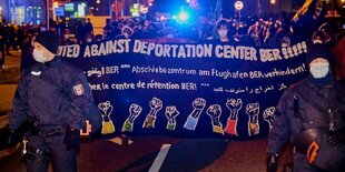 Demonstranten tragen Transparent mit der Aufschrift "United against Deportation Center BER!!!"