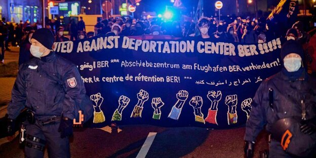 Demonstranten tragen Transparent mit der Aufschrift "United against Deportation Center BER!!!"