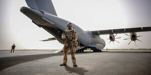 Ein Soldat steht vor einem Bundeswehrflugzeug