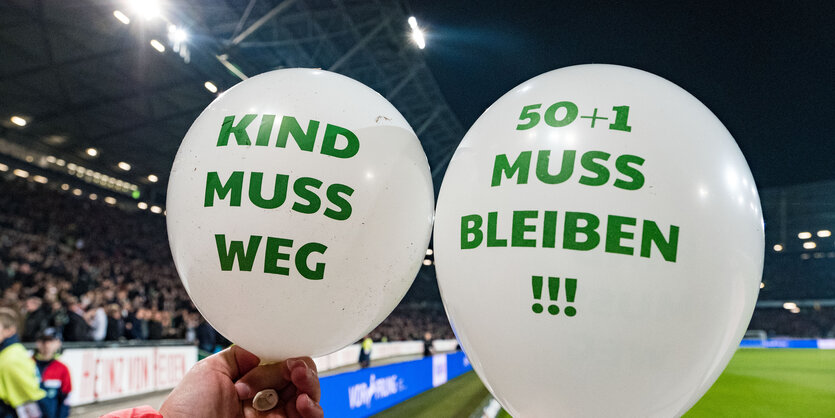 Luftballons mit der Aufschrift "Kind muss weg" und "50+1 muss bleiben" werden in dem Stadion für ein Foto gehalten.