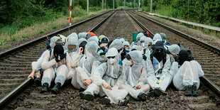 Eine Gruppe in weißen Schutzanzügen auf Bahngleisen