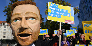 Eine Pappmaché-Figur von Christian Lindner mit einem Schild: FDP: Profite first, Klimaschutz second!