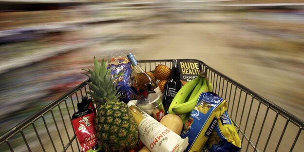 Einkaufswagen mit lauter verschiedenen Lebensmitteln, dahinter alles verwischt