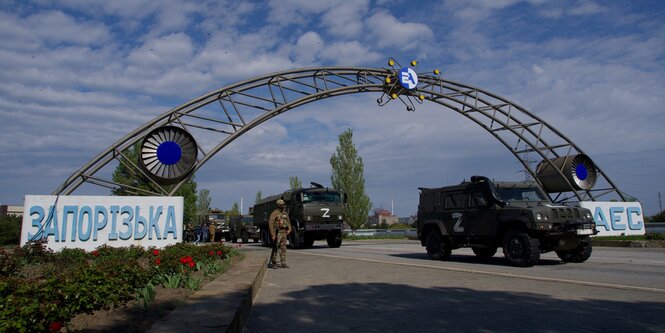 Ein Soldat und mit einem weißen "Z" bemalte Armeefahrzeuge des russischen Militärs stehen im Eingangsbereich des Atomkraftwerks Saporischschja