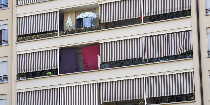 Gartenschirme und geschlossene Balkonjalousien schirmen die Fassade eines Gebäudes ab