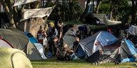 Punks stehen zwischen Zelten und Transparenten in ihrem Camp auf Sylt
