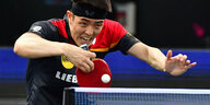Tischtennisspieler Dang Qiu an der OPlatte mit gefletschten Zähnen , bevor er eine Rückhand spielt