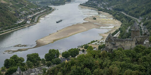 Ein Binnenschiff fährt an freiliegenden Felsen und Sandbänken auf einem Fluss