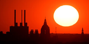 Die Sonne geht in Hannover hinter dem Gaskraftwerk Linden und dem Neuen Rathaus unter