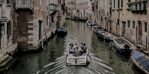 Menschen fahren auf einem Boot in einem Kanal in Venedig