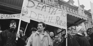 Junge Männer demonstrieren, auf einem Banner steht "Tod dem Teufel Rushdie"