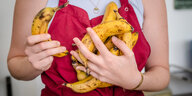 Eine Person hält Bananen vor ihrer Brust