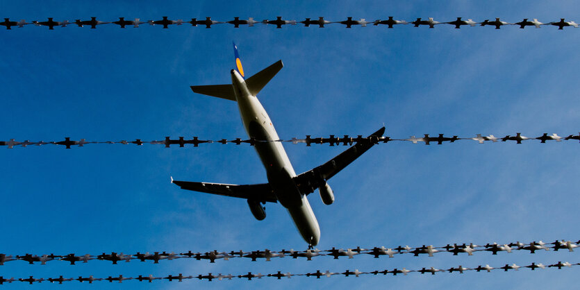 Ein Flugzeug fliegt hinter Stacheldraht