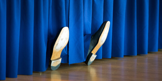 Zwei Schuhe hinter einem Vorhang