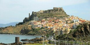 Eine Stadt am Hang auf Sardinien, davor das Meer