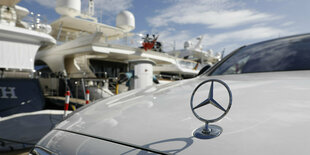 Ein Mercedes-Stern auf einer Kühlerhaube, im Hintergrund eine Yacht