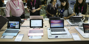 Menschen betrachten neue Laptops auf einem Tisch