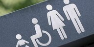 Auf dem Dach einer öffentlichen Berliner Toilette sind Piktogramme für Wickelraum, Behindertentoilette, und Damen-/Herren-WC angebracht