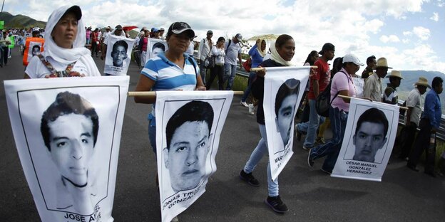 Menschen demonstrieren und zeigen Fotos der verschwundenen Studenten