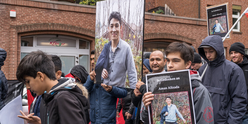 Menschen, die auf der Demo Schilder und Fotos hochhalten