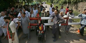 Eine kleine Menschenmenge wartet vor einer Absperrung vor Imran Khans Haus in Islamabad.