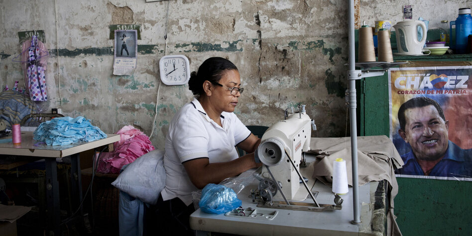 Eine Frau an der Nähmaschine, rechts ein Plakat mit Chavez