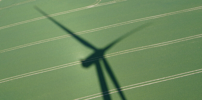 Windrad auf grüner Wiese im Schatten