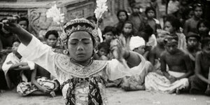 Eine alte schwarz-weiß-Aufnahme: eine indigene Frau tanzt mit geschlossenen Augen, im Hintergrund sitzen viele Zuschauer