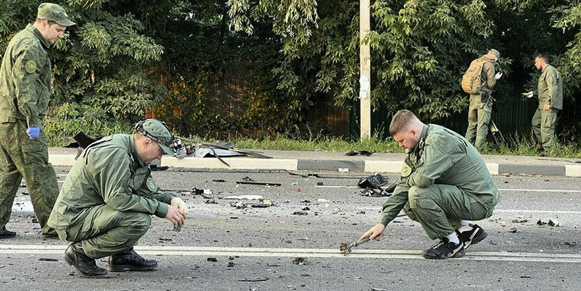 Zwei Männer in Uniform untersuchen den Tatort - ein dritter Mann schaut ihnen dabei zu