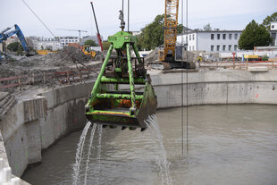 Baggerschaufel hängt über Wasserfläche und tropft