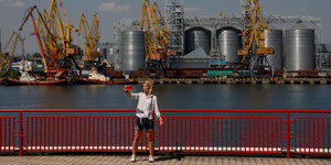 Eine Frau macht ein Selfie, im Hintergrund ein Hafenbecken und große Getreidespeicher