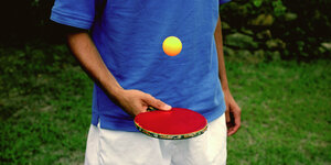 Eine Person jongliert einen Tischtennisball auf einem Schläger