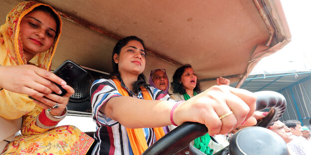 Eine indische Frau fährt mit drei Frauen auf einem Traktor