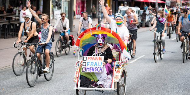 Eine Fahrraddemo mit einem Plakat im Vordergrund: Mann, Frau, Mensch - Mensch ist angekreuzt