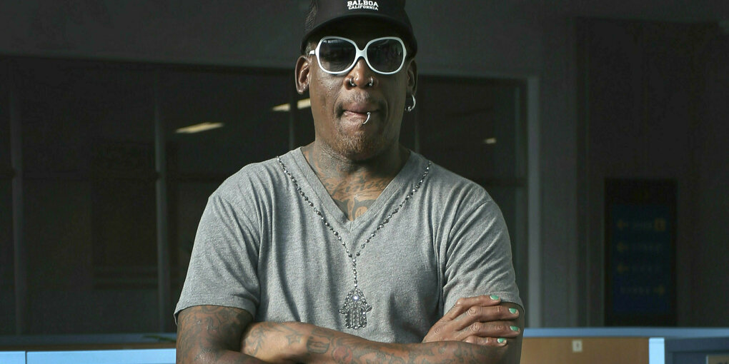 Dennis Rodman mit verschränkten Armen, Sonnenbrille und Basecap