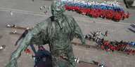 Weiß-blau-rote Luftballons als russische Flagge geformt neben einer Lenin-Statue