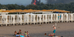 Badende an einem Strand, im Hintergrund brennt es