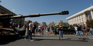 Menschen gehen in Kiew zwischen kaputten russischen Panzern umher