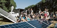 Festivalbesucher sitzen zwischen Solarpanels.
