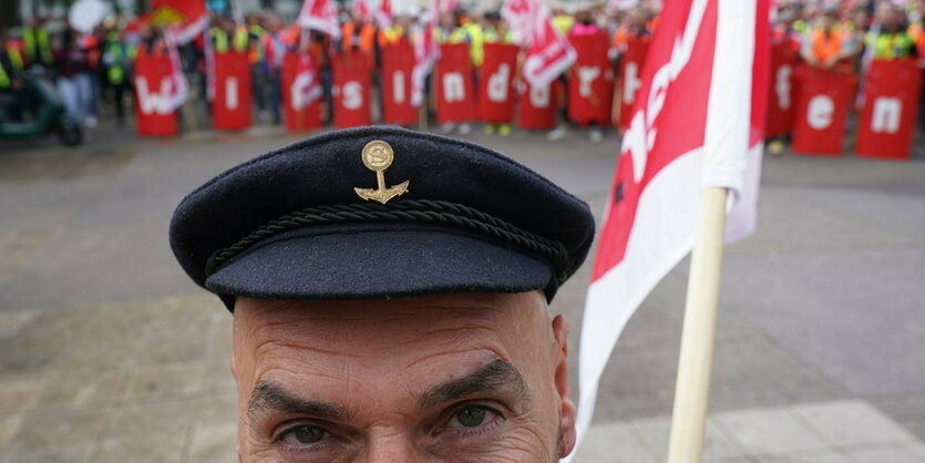 Ein Mann mit Seefahrermütze und Verdifahne steht im Vordergrund, hinter ihm stehen Demonstranten mit Verdi-Flaggen