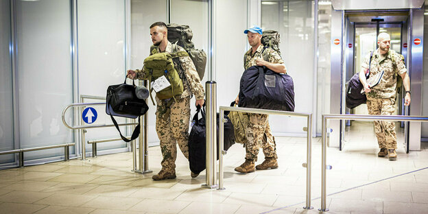 Bundeswehrsoldaten mit Gepäck verlassen die Ankunftszone im Flughafen