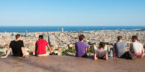 Menschen schauen von einem Hügel auf Barcelona.
