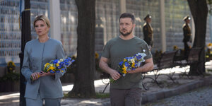 Olena und Vladimir Selenskyi tragen schmale blau-gelbe Blumensträuße in der Hand
