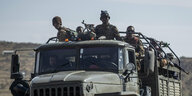Bewaffnete Soldaten sitzen auf einem Militärfahrzeug