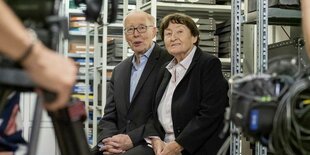 Ulrich und Erika Gregor werden in einem Filmarchiv interviewt, hinter ihnen befinden sich Regale mit Archivkisten, im linken Bildrand ist eine Kamera zu sehen