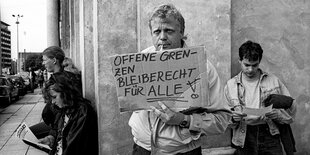 Demonstrant:innen, eine Person hält ein Schild hoch.