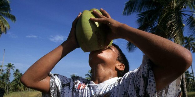 Eine Person trinkt aus einer Kokosnuss.